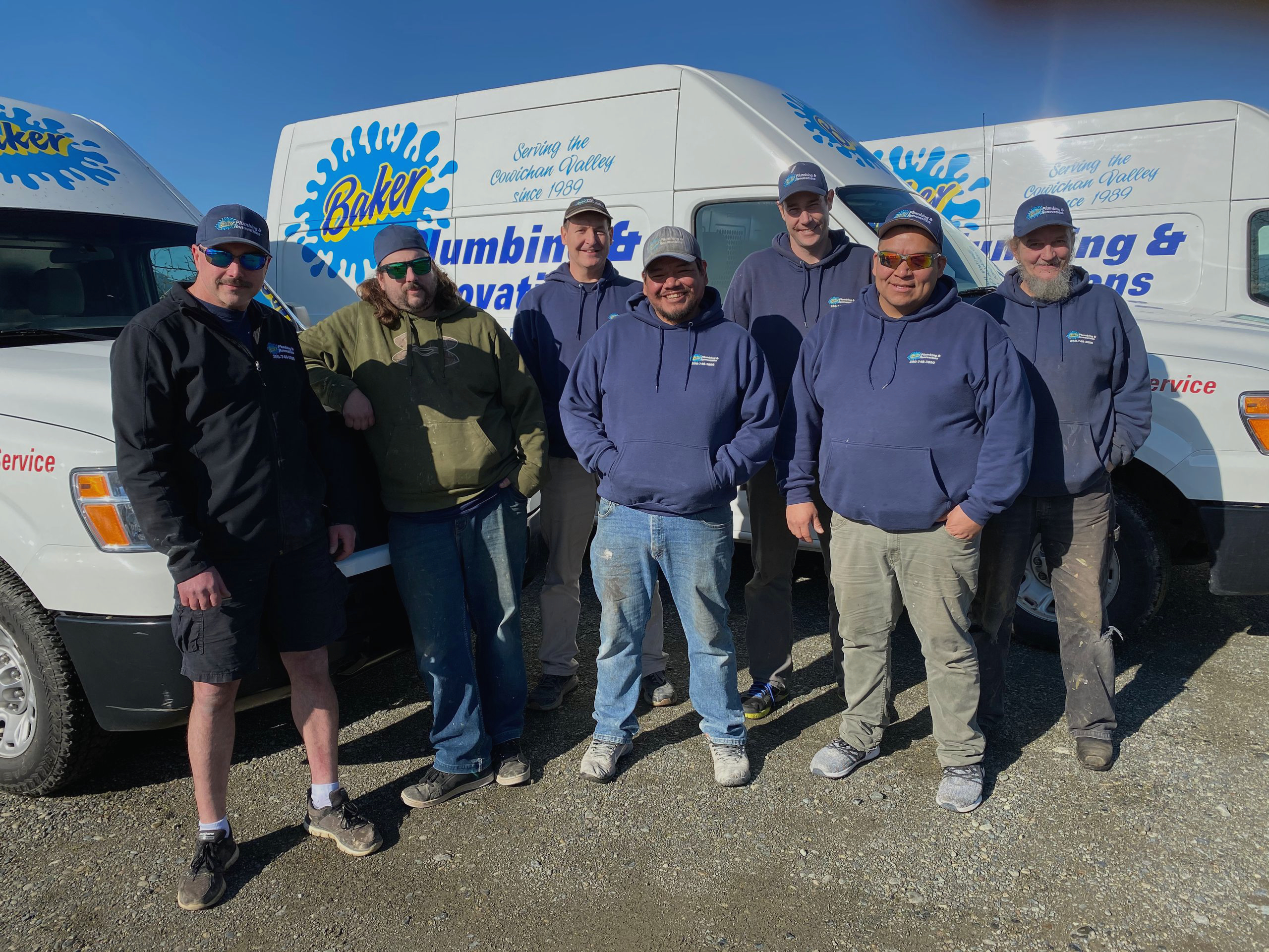 Baker Plumbing team pictured with their branded service vans